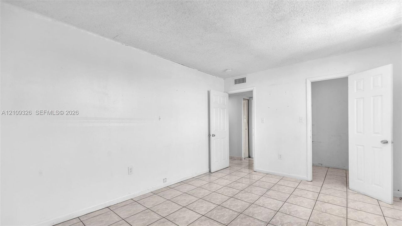 Neutral interior featuring ceramic tile flooring, textured ceiling, and multiple white-paneled interior doors