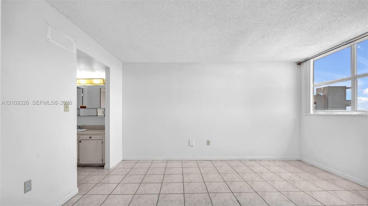 Interior space featuring neutral tile flooring, large multi-pane windows, and high-contrast white walls