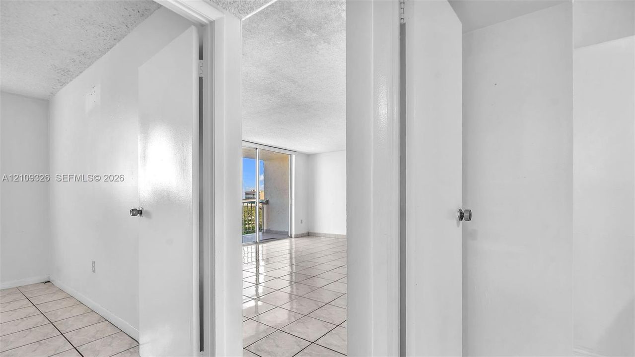 Interior space featuring white walls, neutral tile flooring, and glass sliding doors leading to an exterior balcony