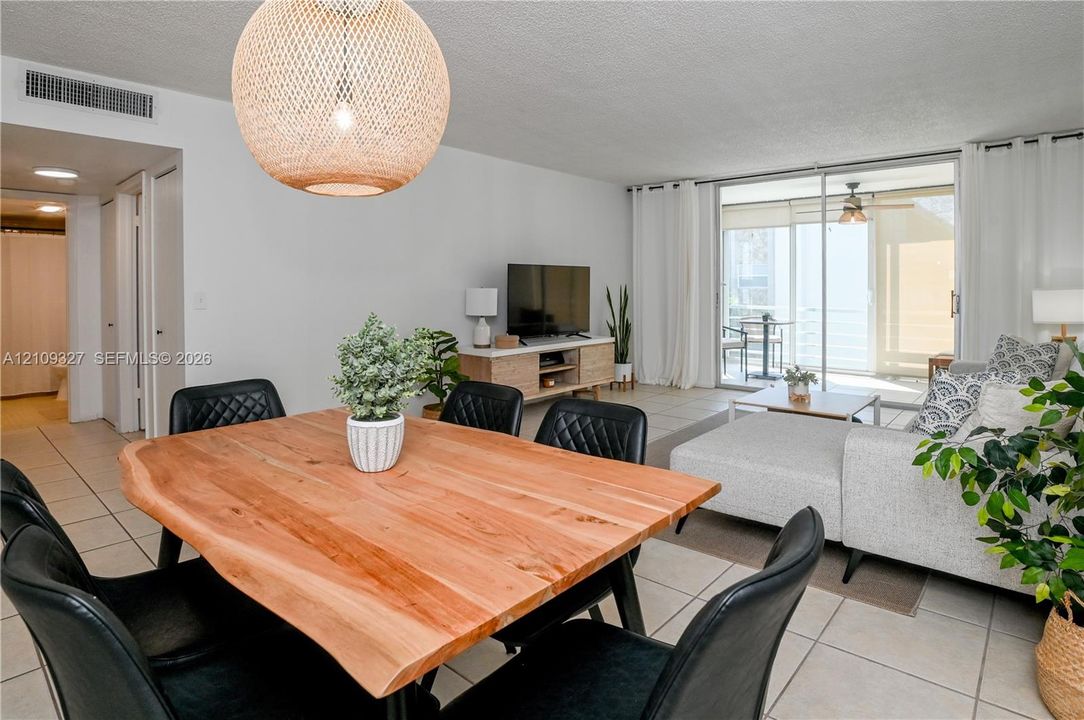 Open-concept living space featuring large-format tile flooring, a woven dome pendant light fixture, and floor-to-ceiling sliding glass doors providing outdoor access