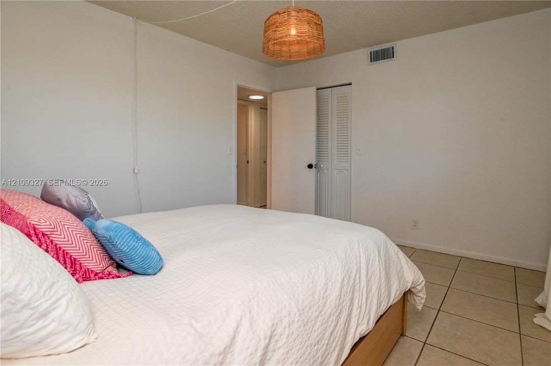 Ceramic tile flooring, louvered bi-fold closet doors, and woven drum pendant lighting