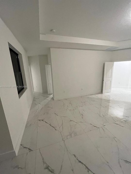 Large-format tile flooring with a marble-pattern finish, recessed tray ceiling, and white panel doors