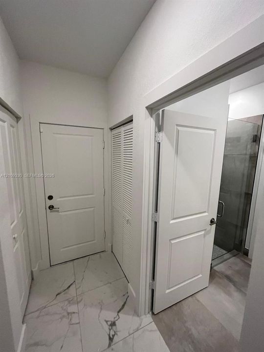 Large-format stone-style tile flooring, solid core two-panel interior doors, and a double-door louvered closet