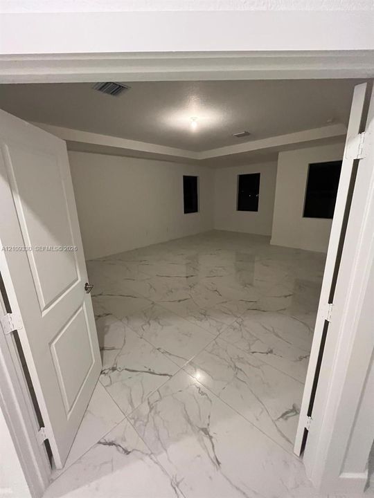 Interior space featuring polished large-format tile flooring with veining, tray ceiling, and double door entry