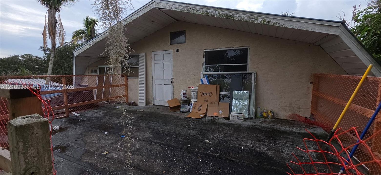 Stucco exterior featuring a pitched roofline, sliding glass window, and a multi-panel door