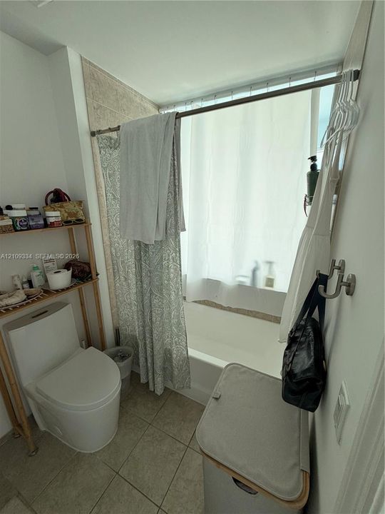 Bathroom featuring a soaking tub, neutral tile flooring, and wall-mounted metal hardware