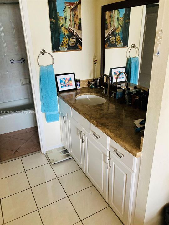 White cabinetry with brushed nickel hardware, stone-finish countertop, undermount sink, and large wall mirror