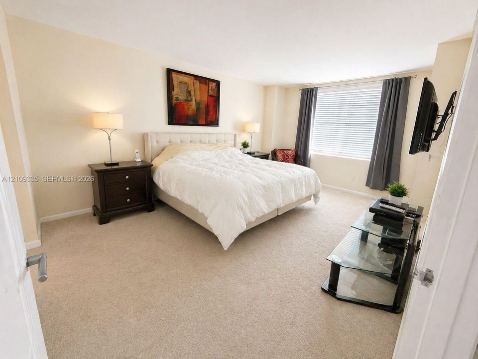 Neutral-toned interior space featuring wall-to-wall carpeting and a window with horizontal blinds