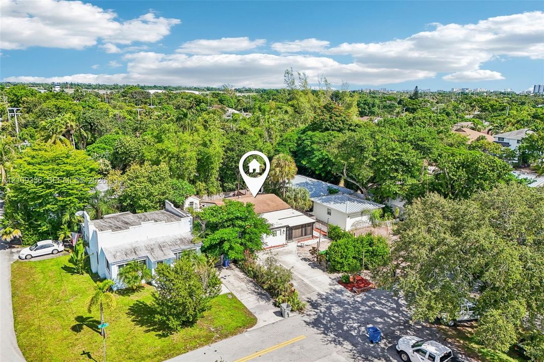 Aerial view of property featuring a shingle roof, concrete driveway, and mature landscaping