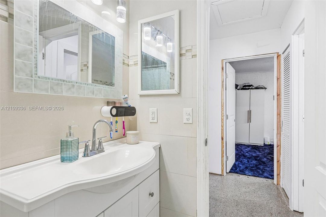 Bathroom vanity featuring an integrated basin, chrome faucet, wall-mounted mirror, and decorative tile backsplash
