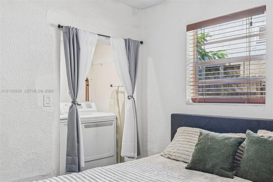 Textured walls and a recessed alcove featuring an integrated laundry hookup with washer
