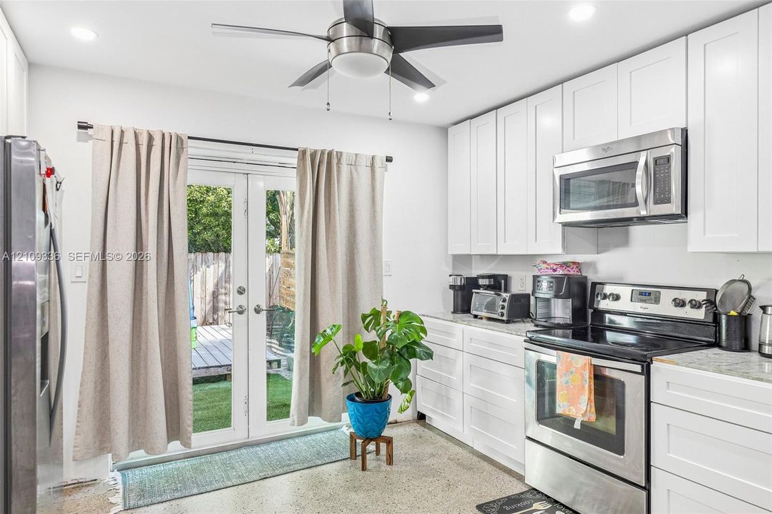 Kitchen featuring white shaker-style cabinetry, stone-finish countertops, stainless steel appliances, recessed lighting, and dual glass-panel doors