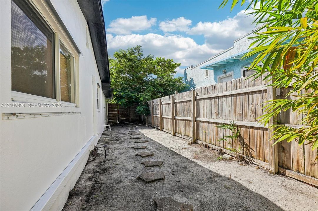 Side yard featuring a smooth stucco exterior finish, horizontal wood fencing, and concrete paver stepping stones