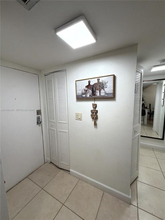 Tile flooring, square flush-mount overhead lighting, and dual louvered-panel closets