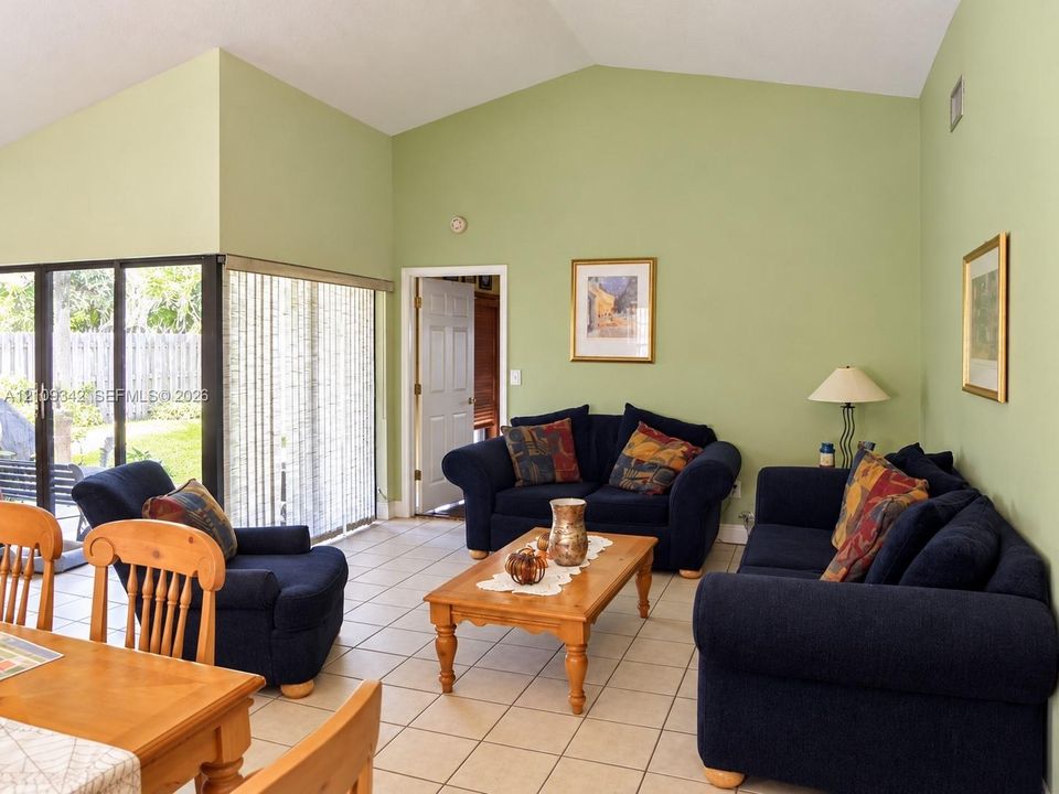 Living area featuring vaulted ceilings, ceramic tile flooring, and large sliding glass doors
