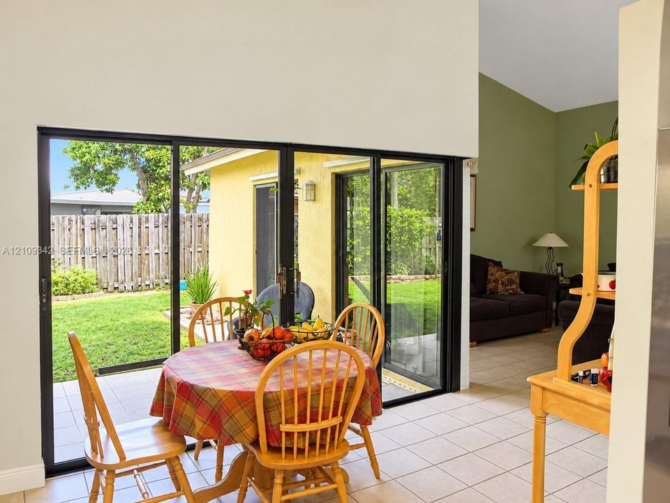 Floor-to-ceiling black-framed sliding glass doors featuring neutral tile flooring and high vaulted ceilings