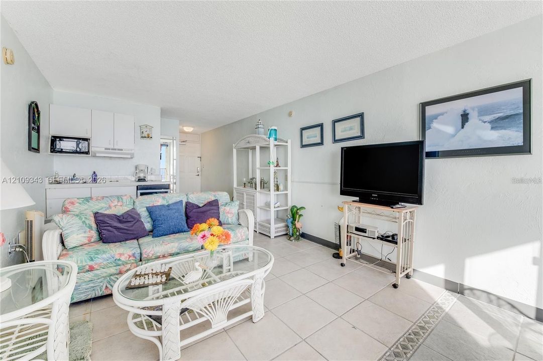 Open-concept living space featuring large-format tile flooring, white cabinetry, and a mounted over-the-range microwave