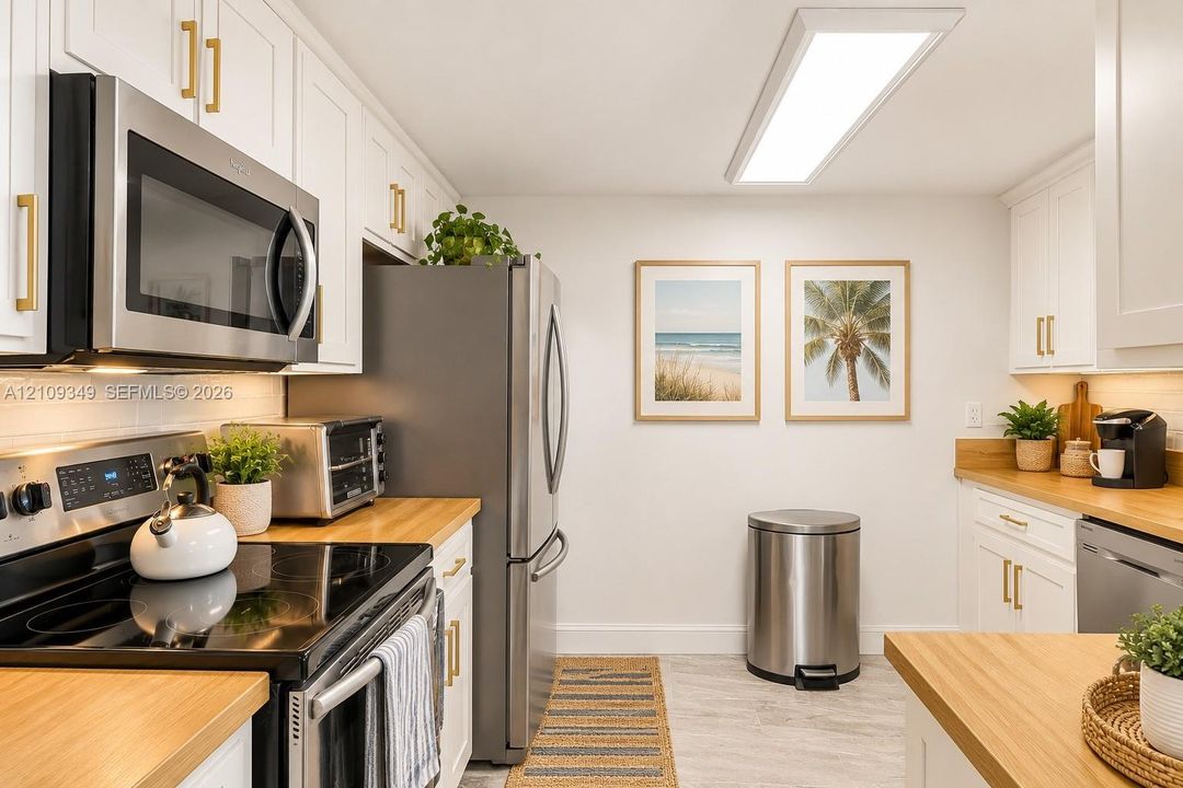 Kitchen featuring white shaker-style cabinetry, wood-finish countertops, stainless steel appliances, and integrated linear LED ceiling lighting