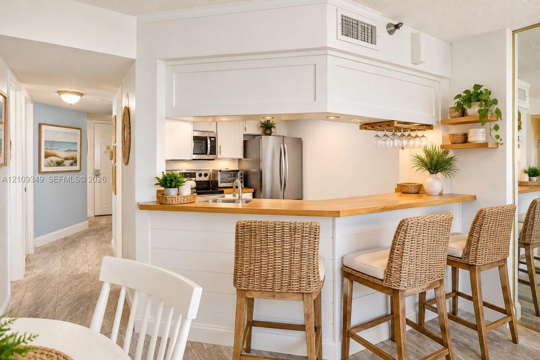 Kitchen featuring white cabinetry, wood-finish breakfast bar counter, recessed lighting, and built-in stemware storage