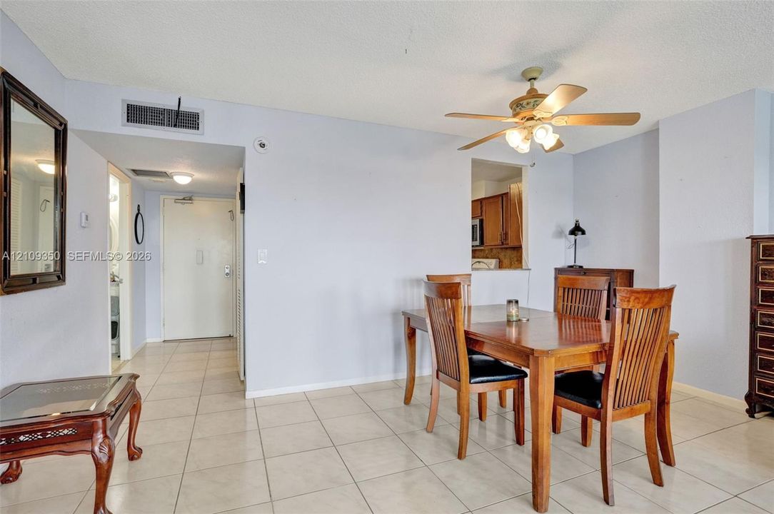 Neutral-toned ceramic tile flooring, ceiling-mounted light fixture with integrated fan, and built-in wall mirror