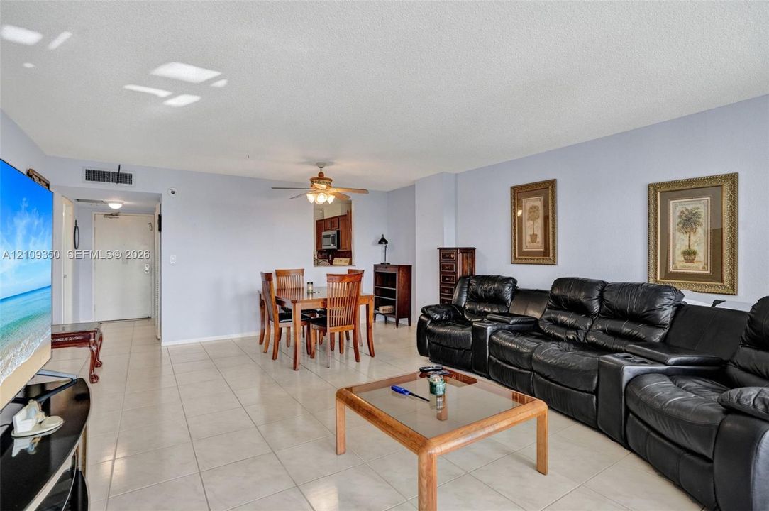 Open-concept main living area featuring light-toned tile flooring, neutral wall paint, and a ceiling-mounted fan with integrated lighting