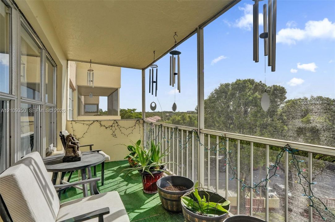Screened-in balcony featuring metal railing, overhead lighting, and solid wall construction