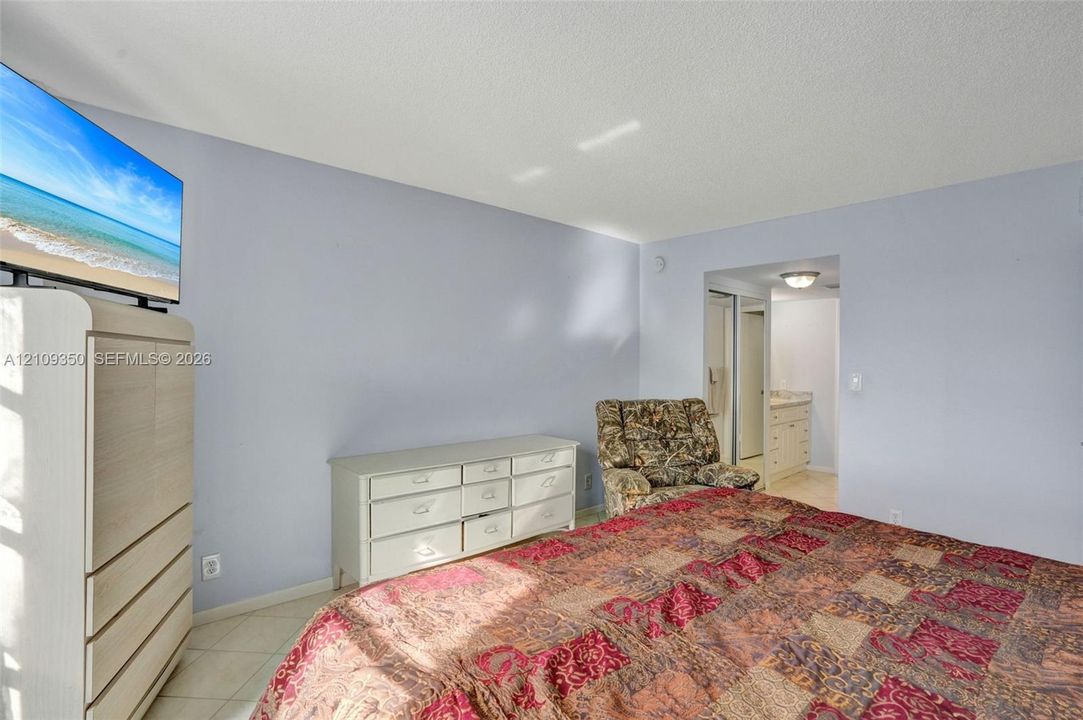 Neutral wall finishes, tile flooring, and a recessed doorway providing a glimpse into a secondary room with built-in cabinetry