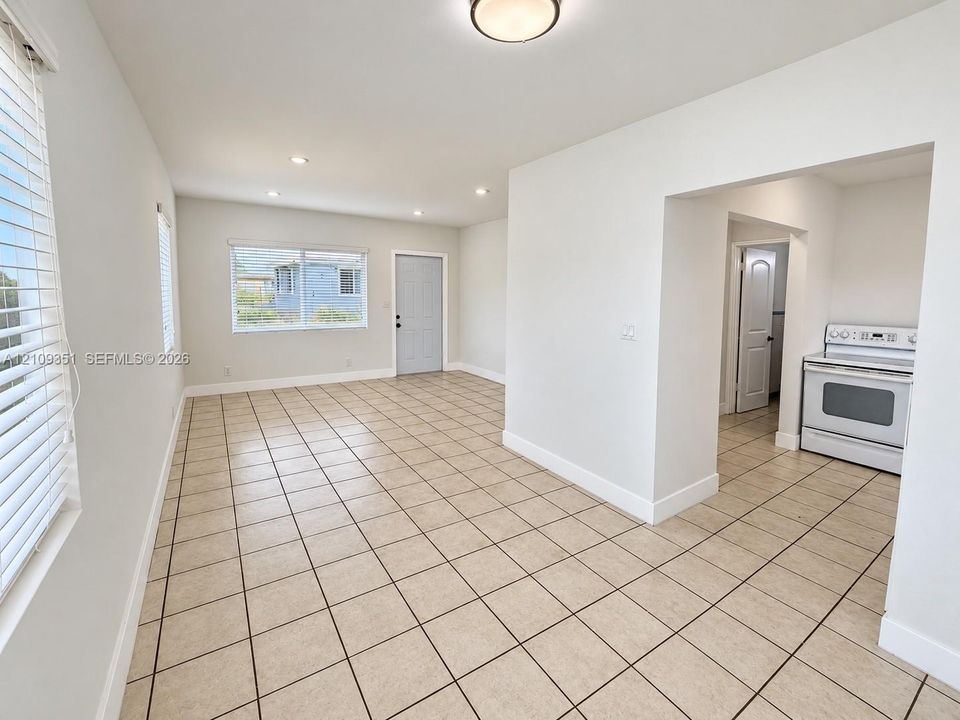 Neutral-toned tile flooring, recessed ceiling lighting, horizontal window blinds, and a built-in range