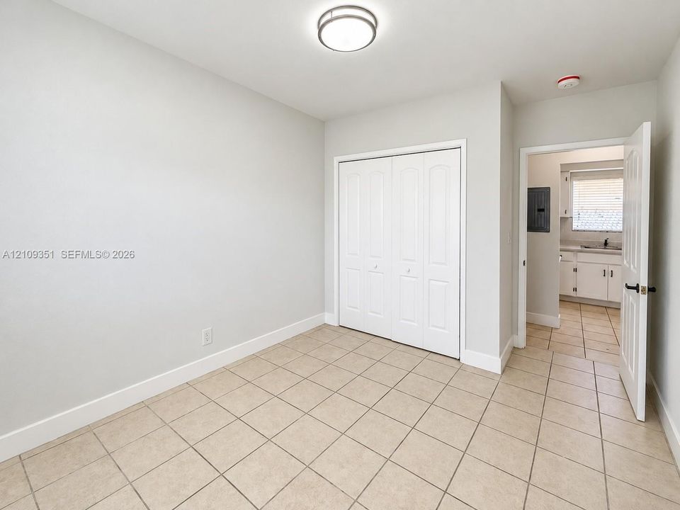 Room featuring ceramic tile flooring, neutral wall paint, and a built-in closet with paneled double doors