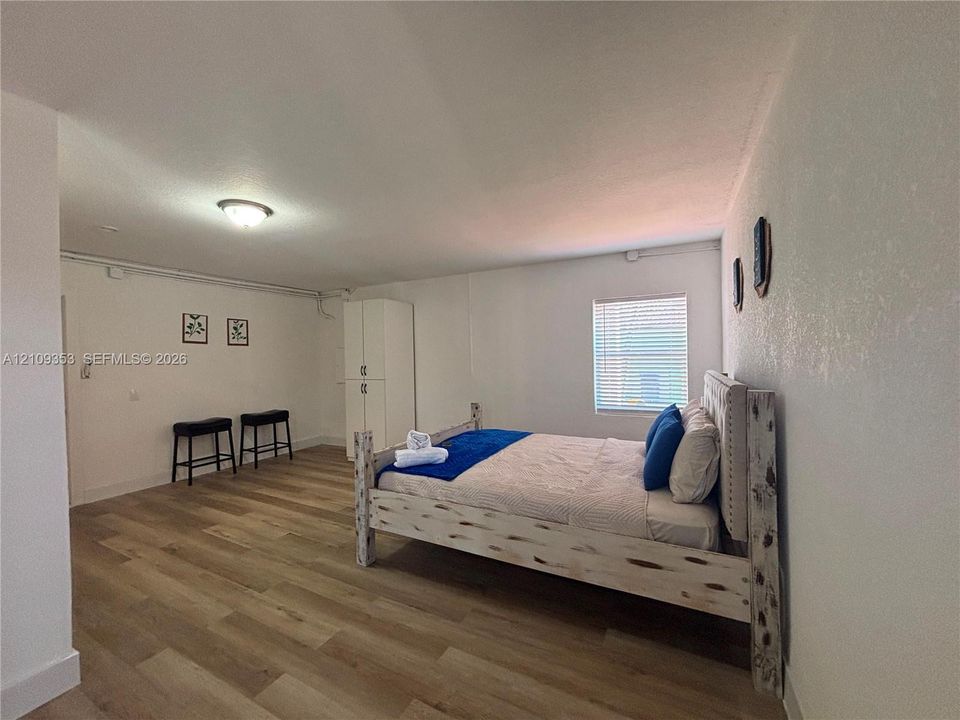 Wood-finish flooring, white-finish built-in cabinetry, and a window with horizontal blinds