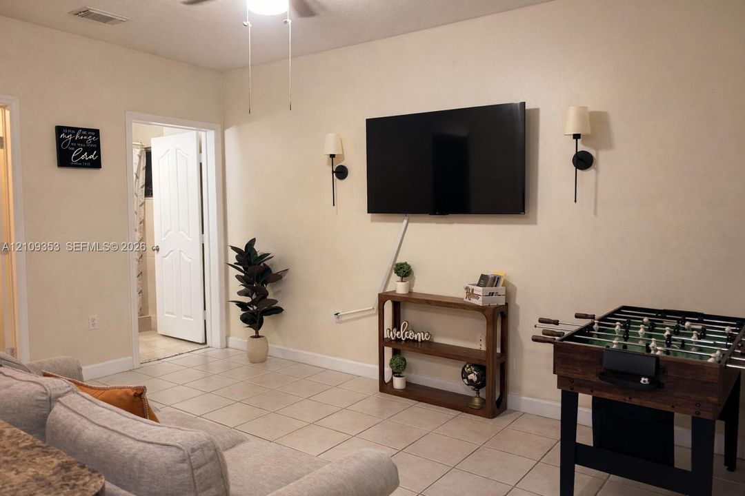 Neutral-toned interior featuring ceramic tile flooring, dual wall-mounted light fixtures, and a six-panel interior door