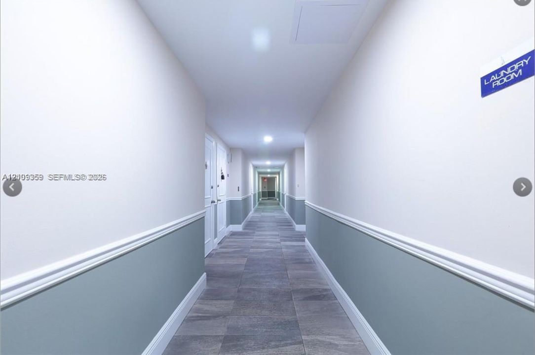 Hallway featuring grey tile flooring, two-tone wall paint, white chair rail molding, and recessed ceiling lighting