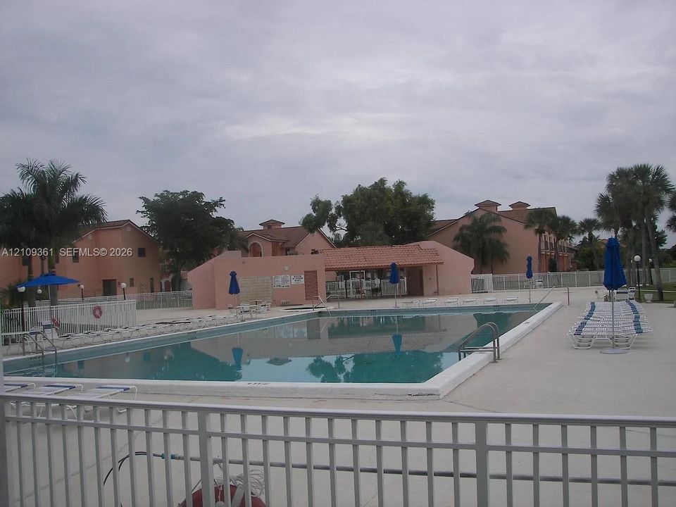 In-ground swimming pool with a concrete deck, covered pavilion, and perimeter fencing