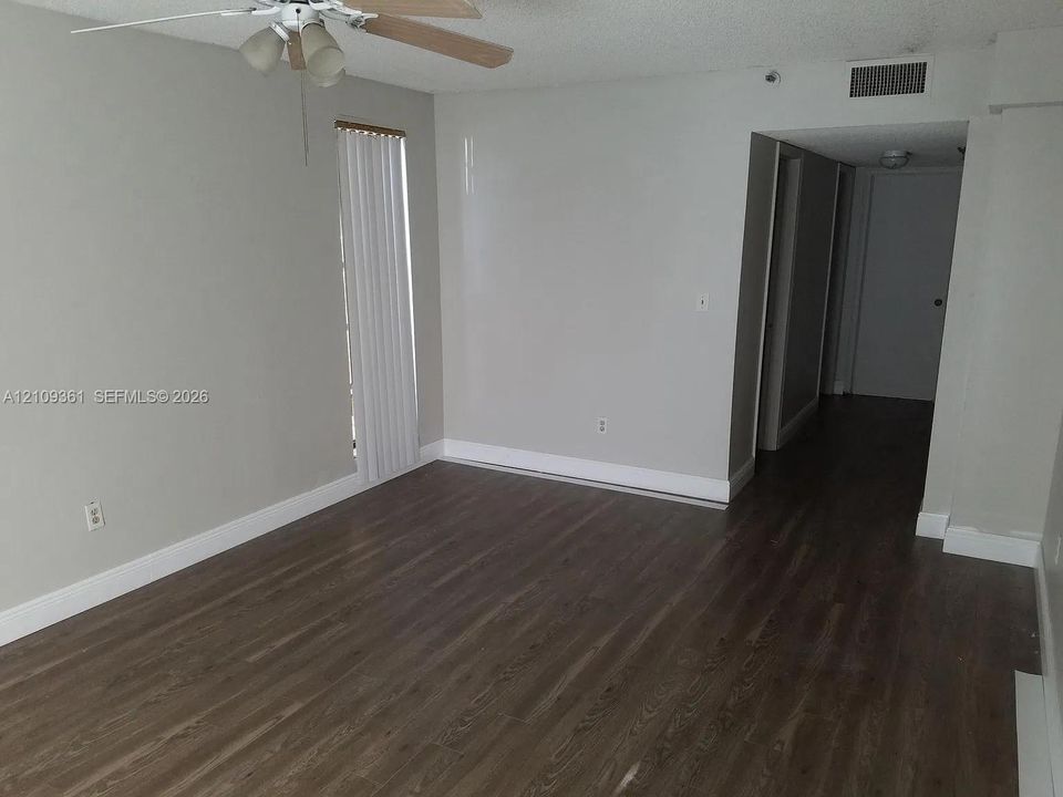 Wood-finish flooring, neutral wall tones, and ceiling fan with integrated lighting