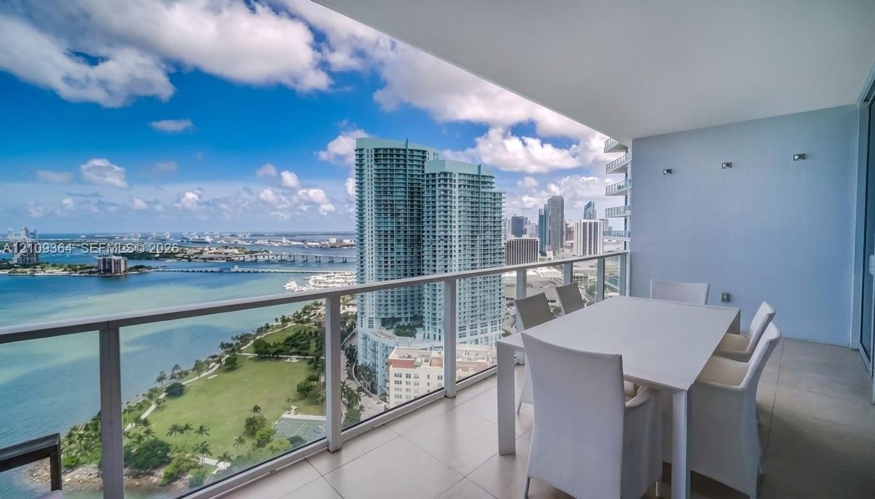 Expansive balcony featuring large-format tile flooring and a glass-paneled railing overlooking the surrounding bay and cityscape