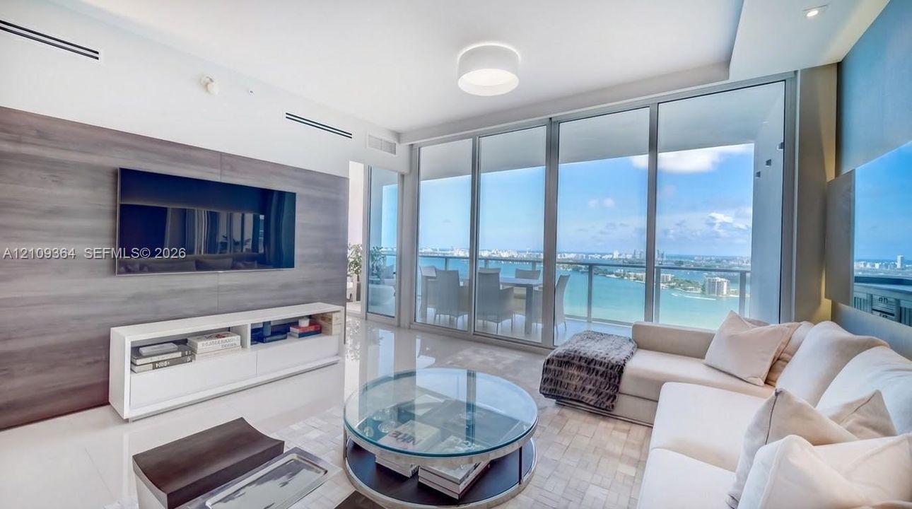 Floor-to-ceiling glass panel walls, wood-finish feature wall, polished tile flooring, recessed ceiling lighting, and private balcony. Accessories are not part of furnishings.