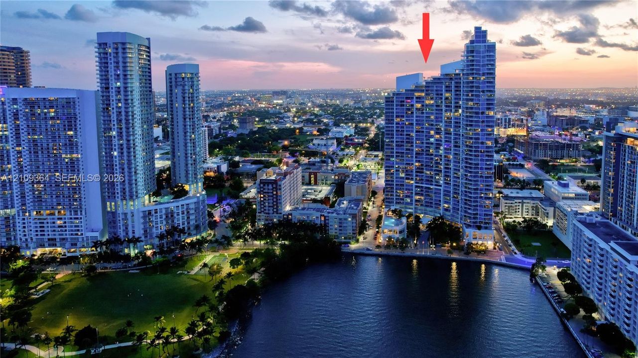High-rise residential tower featuring a tiered architectural design, expansive glass facade, and direct proximity to waterfront and urban park space