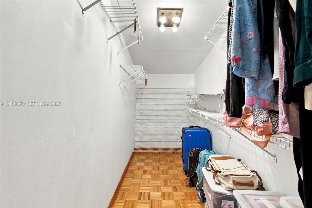 Walk-in storage space featuring parquet wood-finish flooring, multi-level wire shelving, and overhead flush-mount lighting