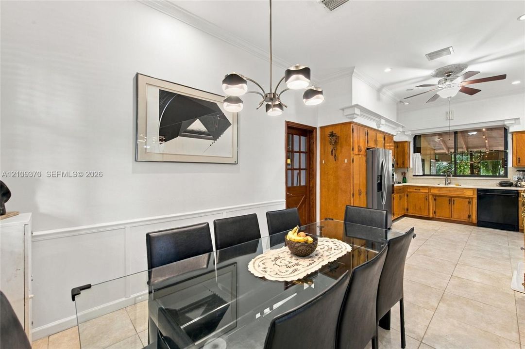Dining area featuring crown molding, wainscoting, and a multi-arm modern chandelier