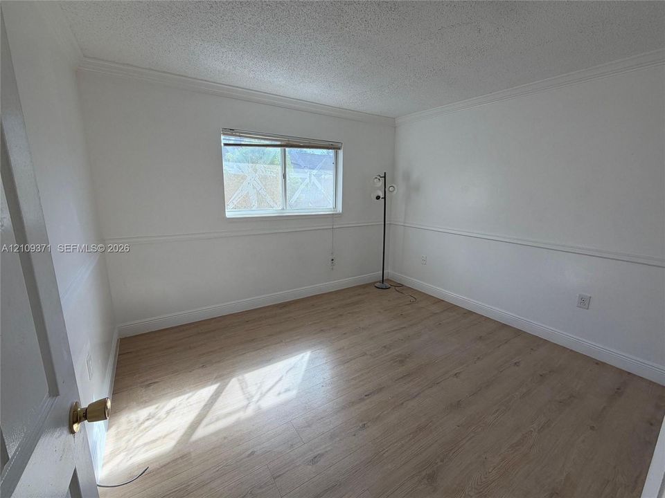 Room featuring wood-finish flooring, chair rail molding, and a single-pane window