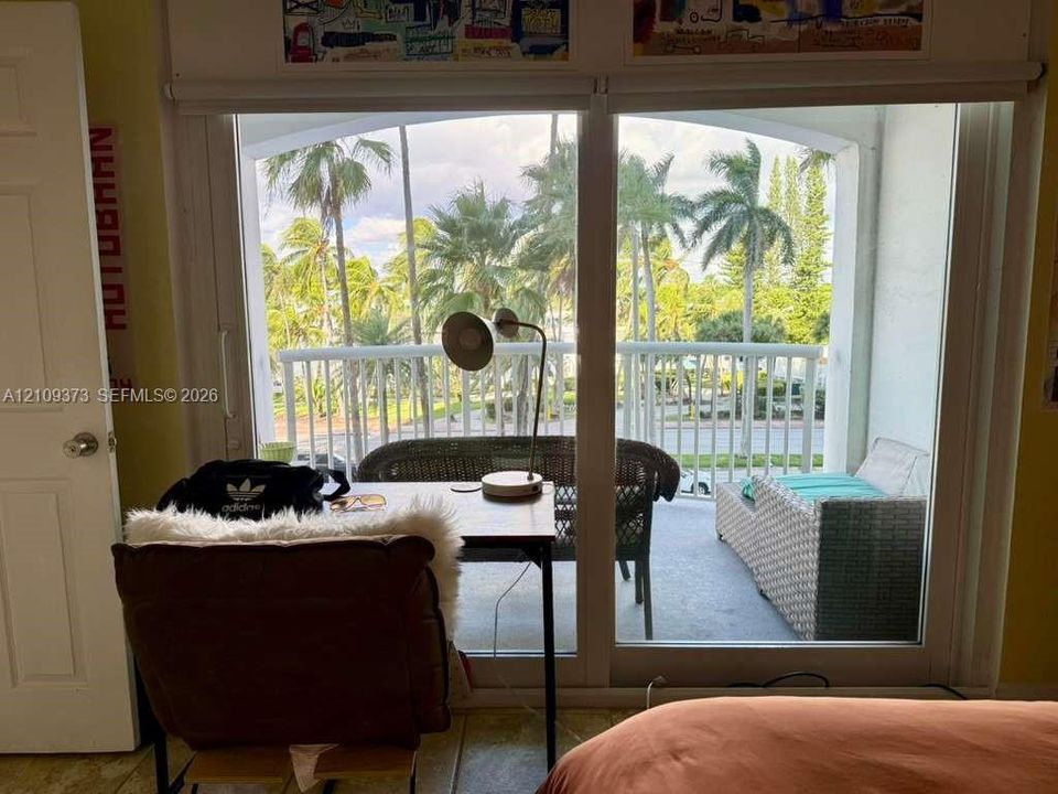 Large floor-to-ceiling sliding glass doors opening to a covered private balcony with vertical white railing