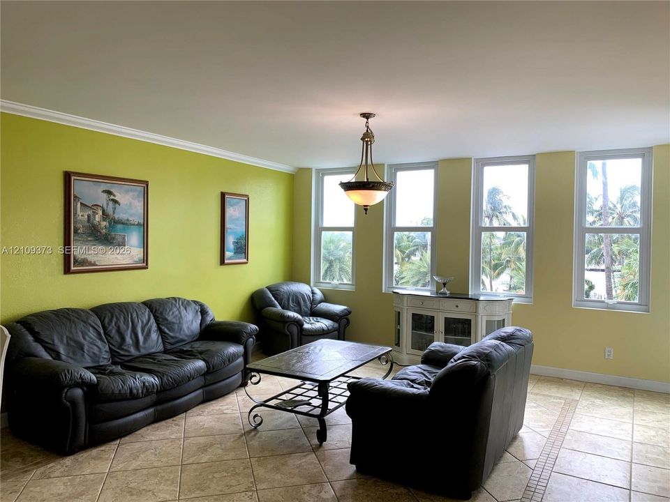 Living area featuring large format diagonal tile flooring, four expansive floor-to-ceiling windows, and a central pendant light fixture