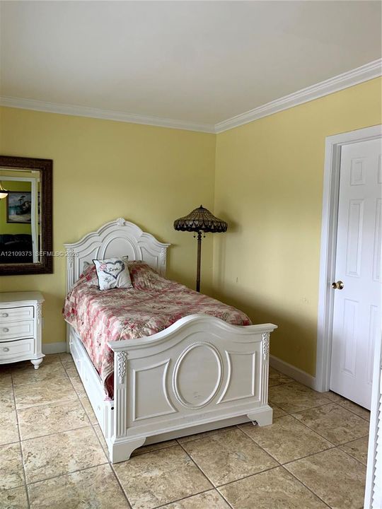 Interior room featuring large-format ceramic tile flooring, crown molding, and a paneled interior door