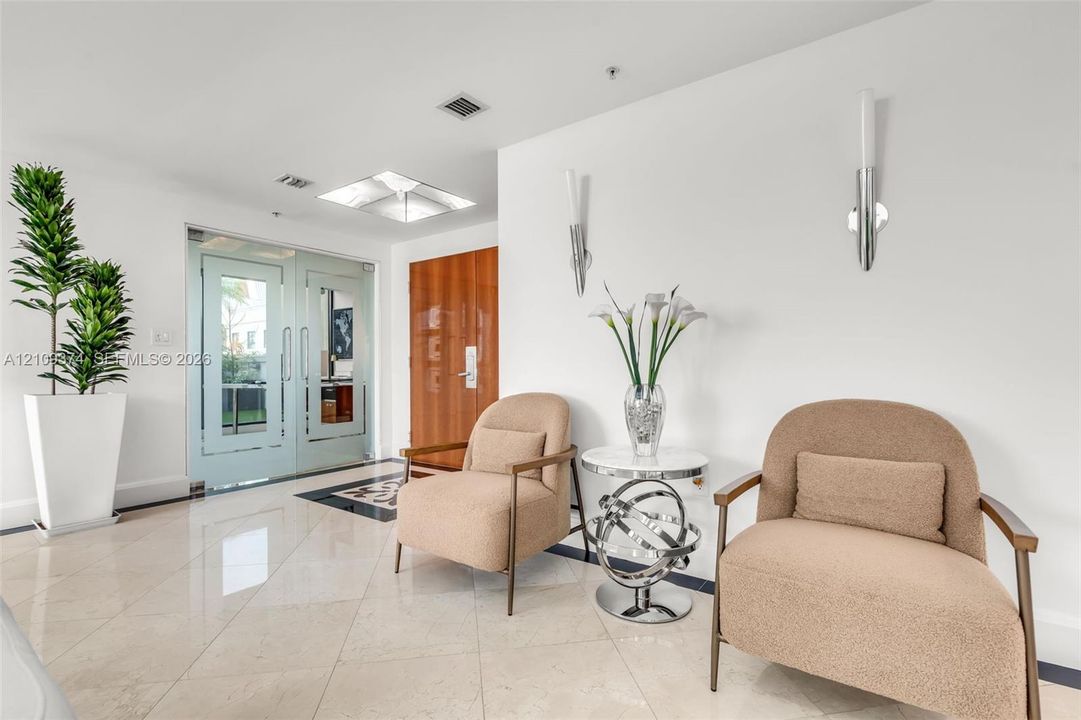 Polished stone flooring, dual glass-paneled entry doors, recessed ceiling lighting, and contemporary wall-mounted light fixtures