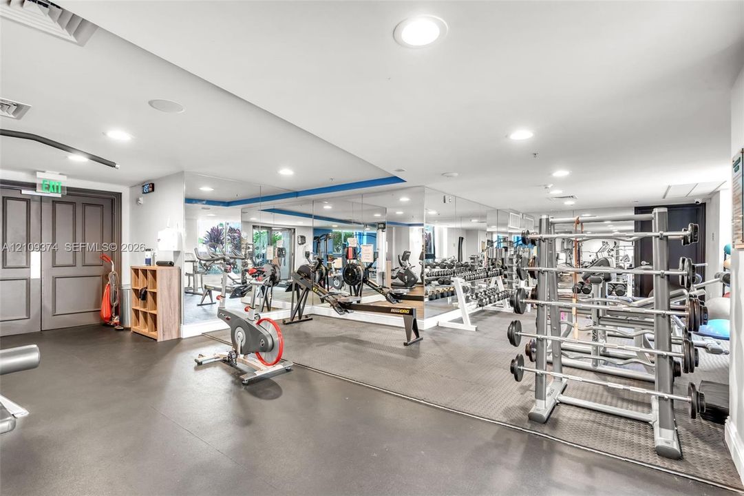 Fitness facility featuring wall-to-wall mirrors, recessed lighting, double-door entry, and resilient rubber flooring