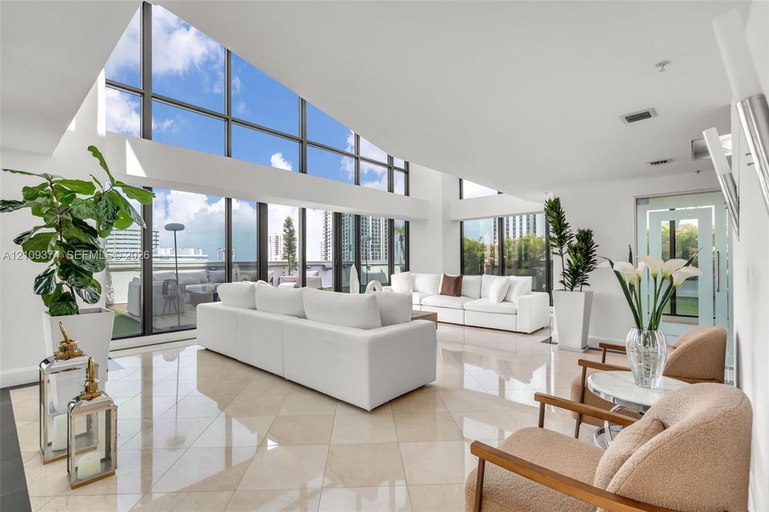 Vaulted ceilings featuring expansive floor-to-ceiling windows and polished stone tile flooring