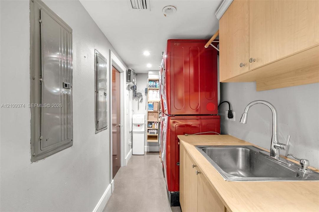 Utility room featuring light-finish cabinetry, a stainless steel sink with a high-arch pull-down faucet, and dedicated built-in shelving