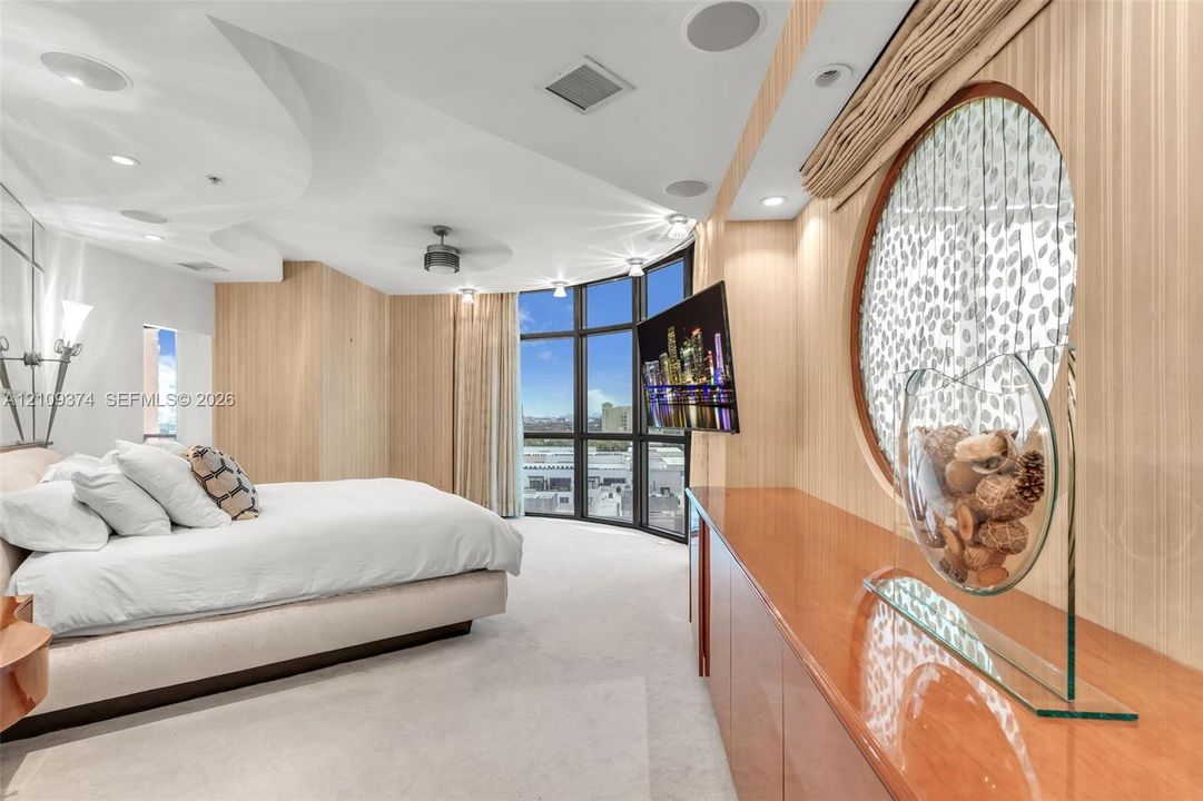 Floor-to-ceiling windows with panoramic exterior exposure, curved architectural ceiling detail, built-in cabinetry with high-gloss finish, circular wall accent, and integrated audio speakers