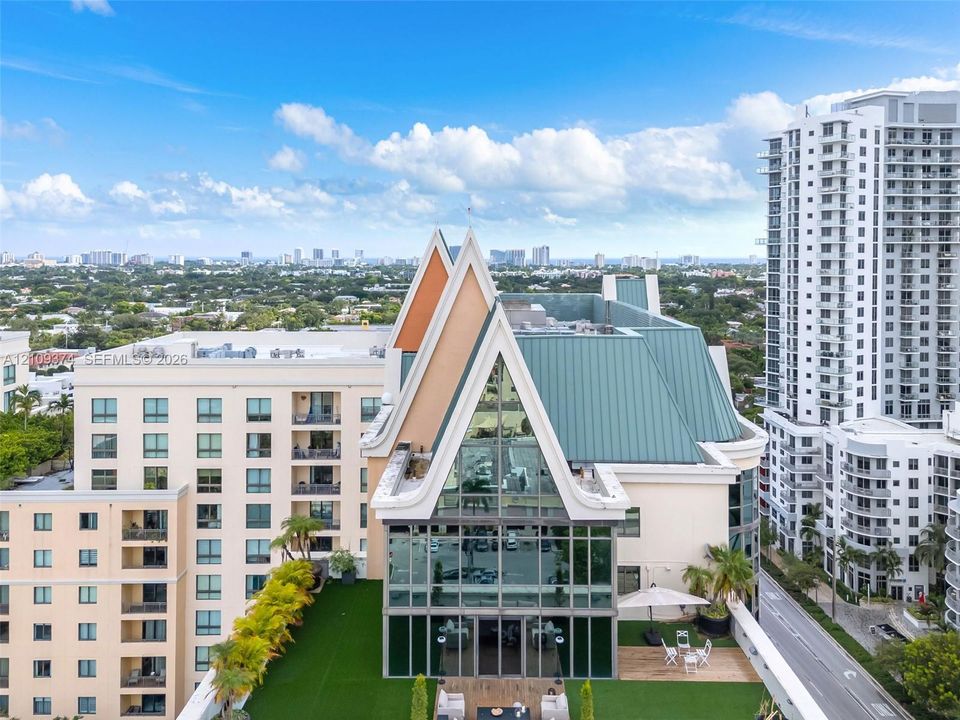 High-rise penthouse featuring an A-frame architectural design, expansive glass curtain wall, metal roofing, and a private rooftop terrace with artificial turf