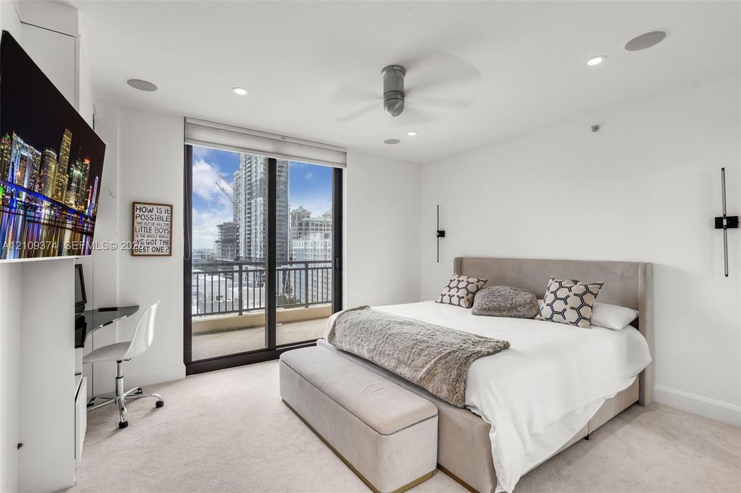 Floor-to-ceiling glass sliding doors, private balcony, recessed lighting, ceiling fan, and wall-mounted light fixtures